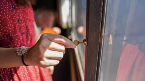 Una mano girando un picaporte de bronce.