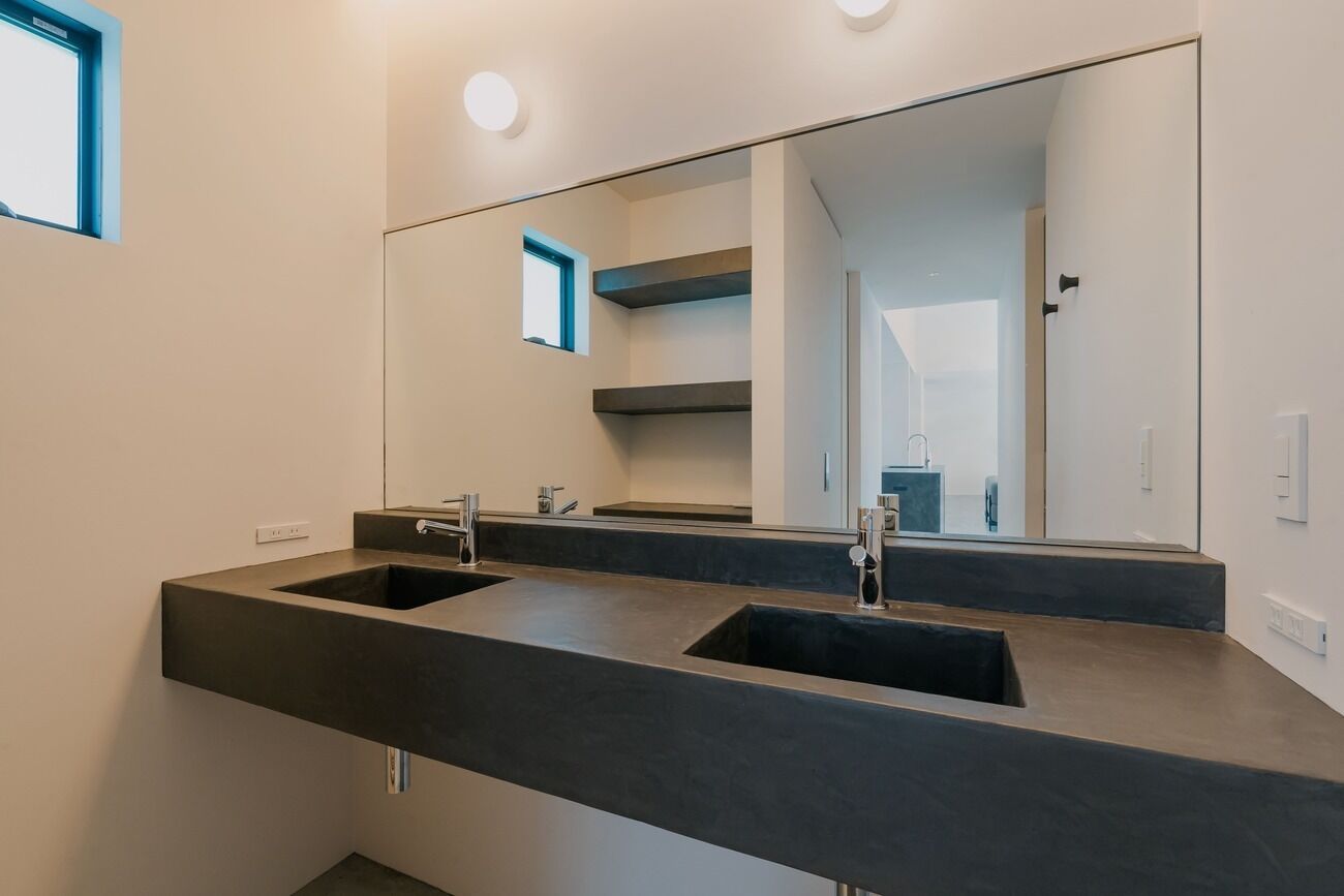 Une salle de bain moderne avec deux lavabos, un grand miroir et une fenêtre.