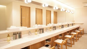 Un baño amplio y moderno con varios lavamanos, puertas de madera y un espejo largo.