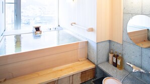 A modern bathroom with a wooden bathtub, a large mirror, and a granite countertop. - Hotel Ladies Plaza Yokote (Yokote)