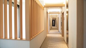 A modern hotel hallway with wooden paneling, carpeted floors, and a sign indicating a shower room and toilet. - Hotel Ladies Plaza Yokote (Yokote)