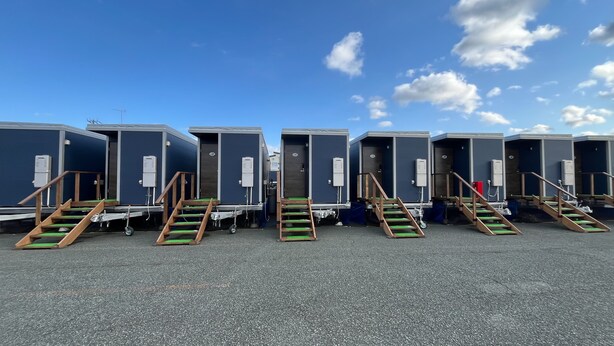 Uma fileira de unidades móveis modulares, cada uma com escadas externas, porta e uma pequena janela.