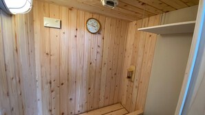 A wooden-paneled room with a thermostat, a clock, and a small shelf. - 730 Hotels (Ishigaki)