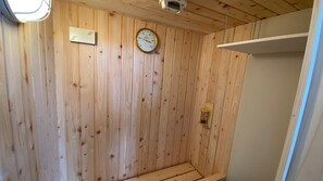A wooden-paneled room with a thermostat, a clock, and a small shelf. - 730 Hotels (Ishigaki)