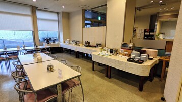 Un comedor para desayuno con mesas, sillas y una barra de buffet.