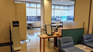 Un hall de hotel con mostrador de recepción, zona de estar y vistas a la calle.