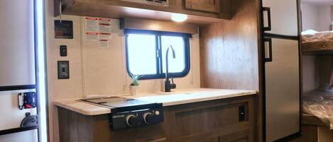 Une petite cuisine équipée d’un four à micro-ondes, d’une cuisinière et d’un évier.