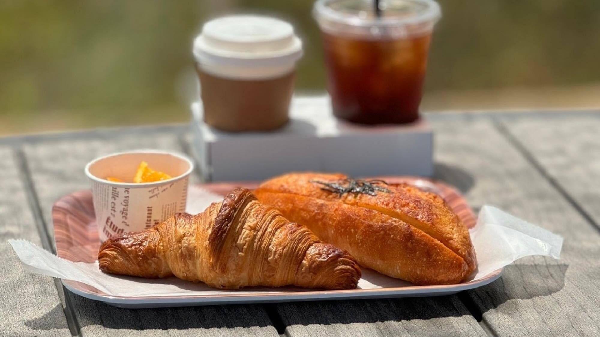 A croissant and a cup of coffee on a wooden table.