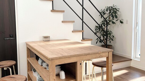 Una mesa de madera con un banco, una escalera y una planta en maceta.