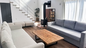 Una sala de estar moderna con una escalera, un sofá, una mesa de centro y una chimenea.