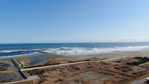 Un paisaje costero con playa, carretera y construcciones industriales.