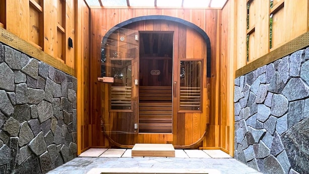 Un espace de détente en bois avec un mur en pierre, une porte en bois et une petite piscine.