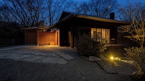 Une maison moderne avec un chemin de pierre menant à l’entrée, entourée d’arbres et bordée d’une allée en gravier.