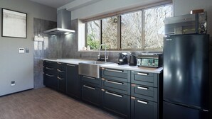 Une cuisine moderne avec des meubles de couleur sombre, un évier en acier inoxydable et un réfrigérateur noir.
