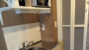 Une cuisine compacte équipée d’un évier, d’un four à micro-ondes, d’une bouilloire et d’un petit réfrigérateur.