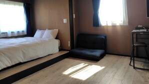 Une chambre comprenant un lit, un petit coin salon, un bureau et une fenêtre avec des rideaux.