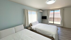 Hotellihuone, jossa on kaksi sänkyä, televisio ja ikkuna, jossa on verhot.