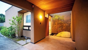 A modern building with a wooden ceiling, a small outdoor garden, and a pathway leading to the entrance. - Villa Revolla (Makinohara)