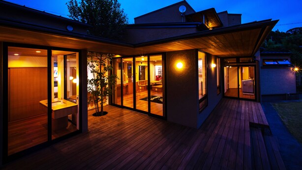 A modern house with large glass doors leading to a wooden deck and a cozy interior. - Villa Revolla (Makinohara)