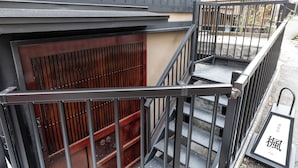 Un escalier avec des rampes en métal, une porte en bois et une enseigne avec des caractères japonais.