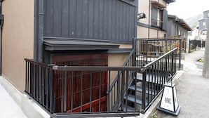 Un immeuble résidentiel doté d’une façade en bois, d’un escalier en métal noir et d’un petit espace extérieur agrémenté d’une enseigne.