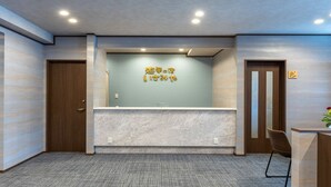 A reception area with a marble counter, a wooden door, and a wall with a sign. - Ryokan-isamiya (Soma)