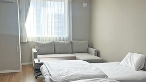Un dormitorio moderno con dos camas, un sofá y una ventana con cortinas translúcidas.