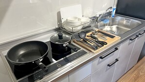 Una cocina moderna con estufa, ollas, escurreplatos y utensilios.