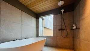 A modern bathroom with a freestanding bathtub, a shower, and a window providing natural light. - Cottage Nil/noi (Masuda)