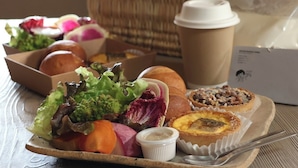 A tray with various food items, a coffee cup, and a basket in the background. - Cottage Nil/noi (Masuda)