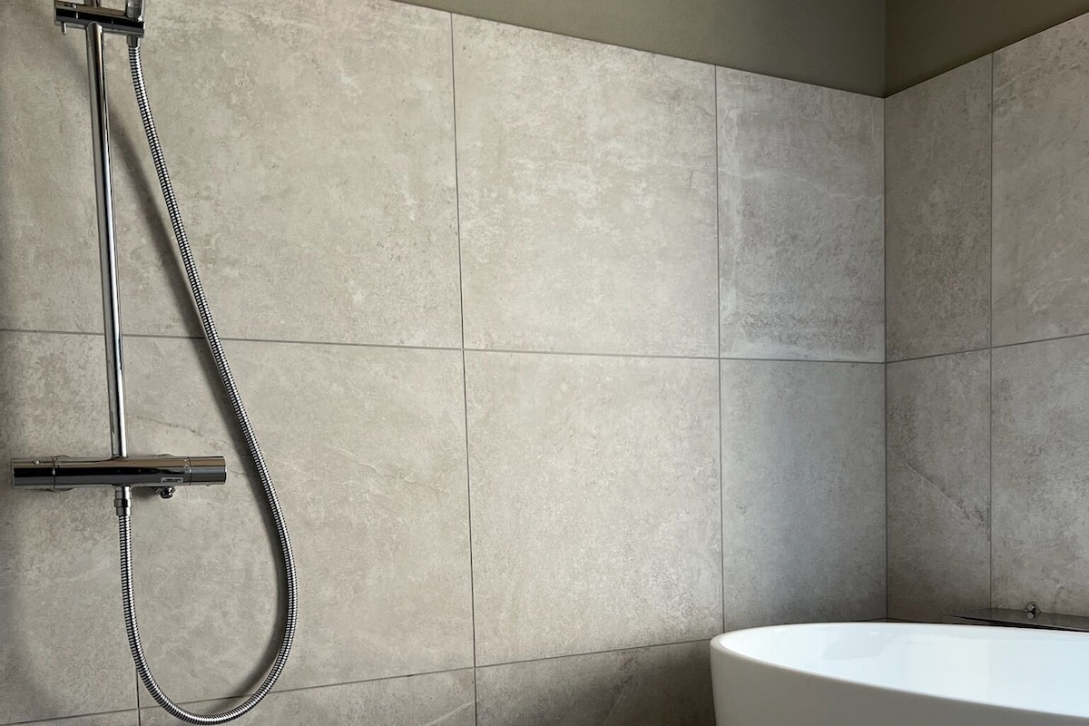 A modern bathroom with a freestanding bathtub, a showerhead, and a tiled floor.