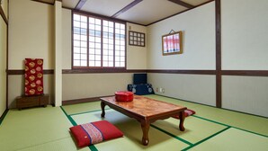 A tatami mat room with a low wooden table, a red cushion, and a window with a view. - Ryotei Yoshinoya (Matsuura)