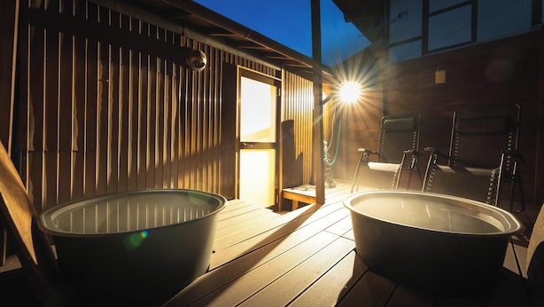 A wooden deck with two large tubs, a bench, and a table with chairs. - Teihaku Chichibu Nagatoro Folk House Rental (Nagatoro)