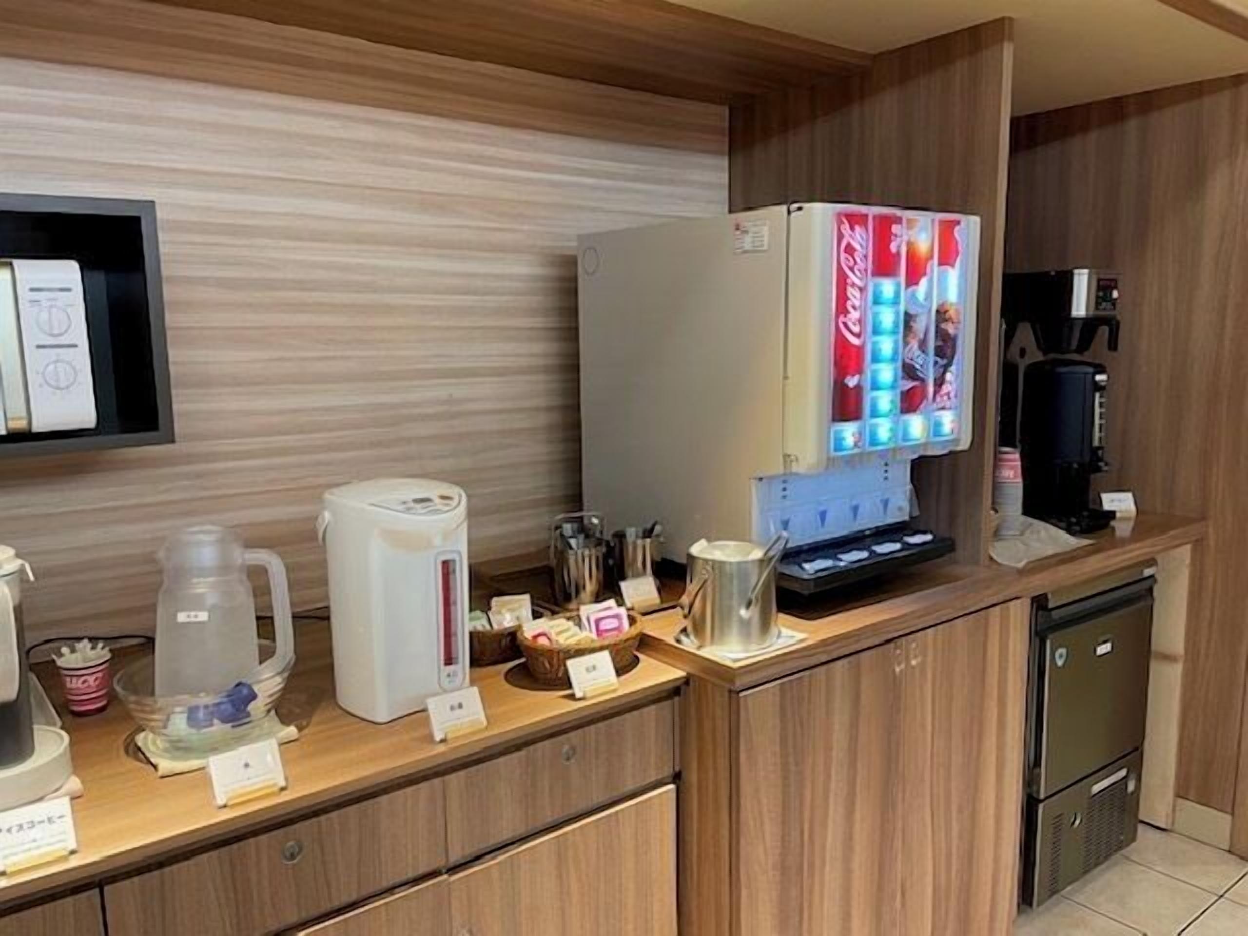 A kitchen area with a refrigerator, coffee machine, and a microwave.