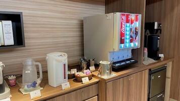A kitchen area with a refrigerator, coffee machine, and a microwave.