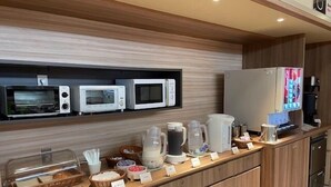 A buffet area with various food items and appliances like microwaves and a coffee machine. - Hotel Park Inn Takaoka (Takaoka)
