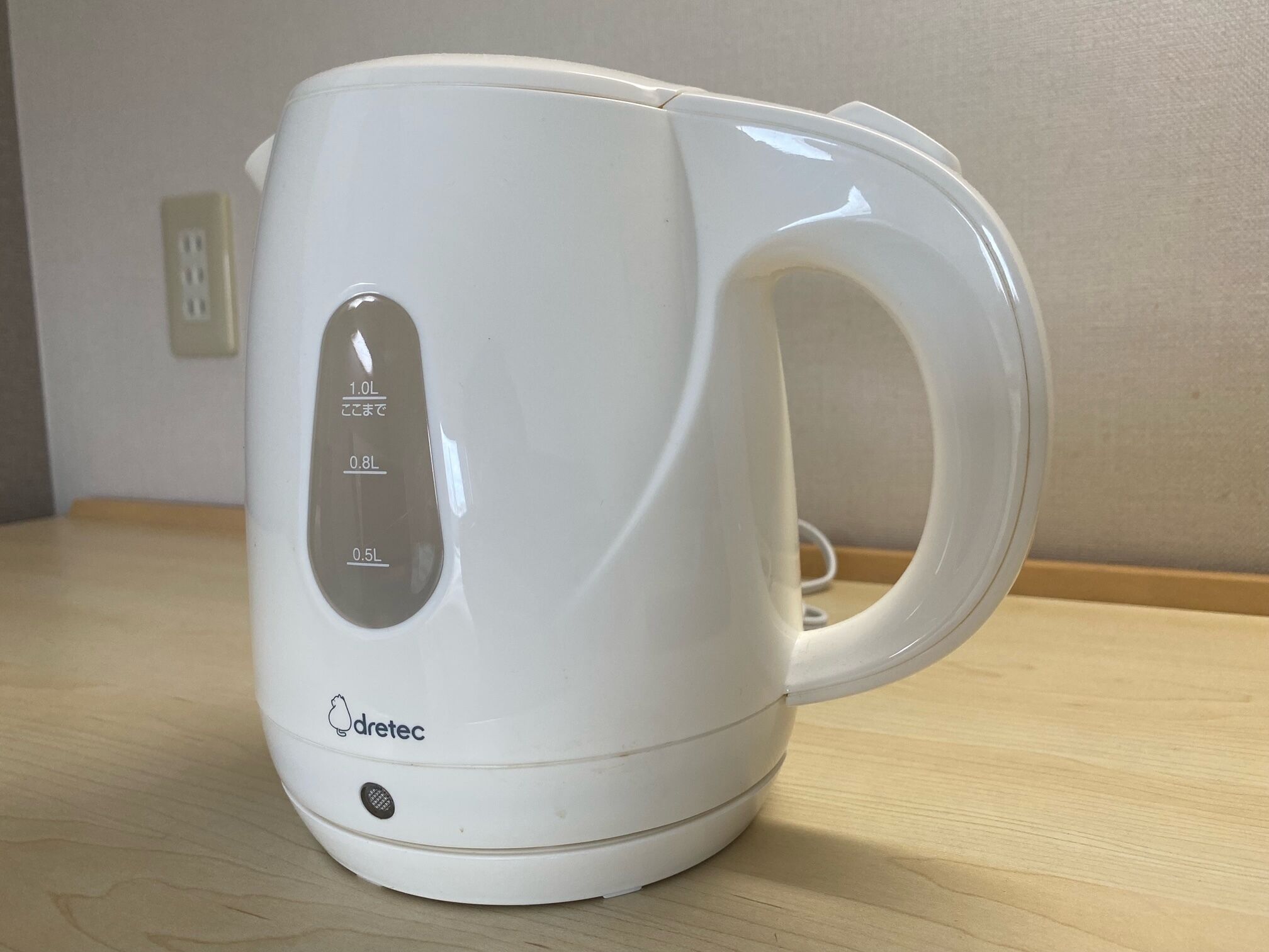 A white electric kettle with measurement markings and the brand 'dretec' on a wooden surface.