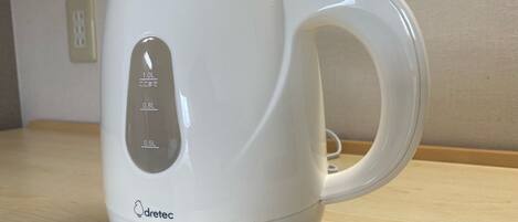 Une bouilloire électrique blanche, dotée de repères de mesure et de la marque « dretec », posée sur une surface en bois.