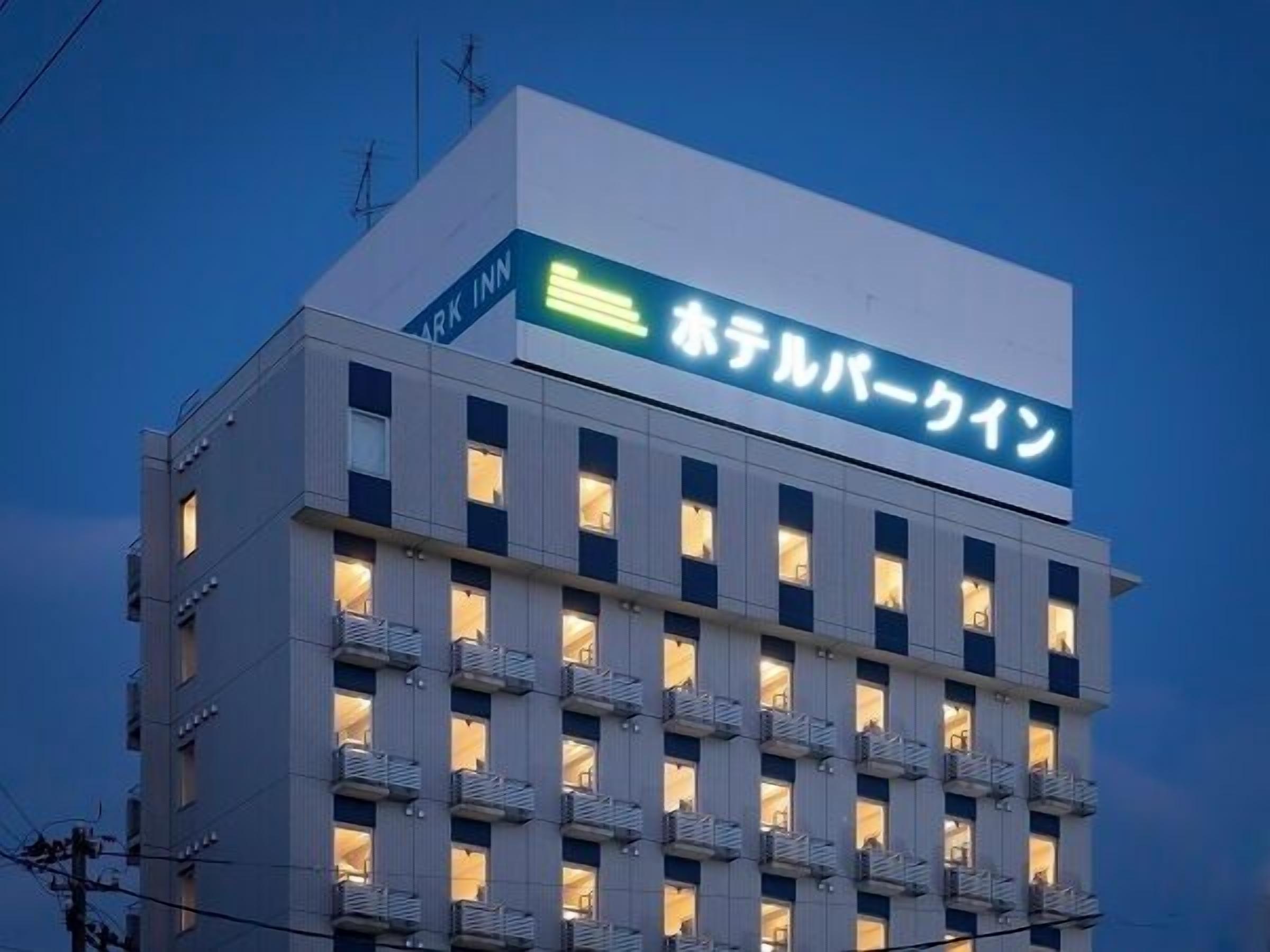 A hotel building with a sign in Japanese, multiple balconies, and a modern architectural style.