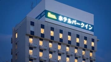 A hotel building with a sign in Japanese, multiple balconies, and a modern architectural style.
