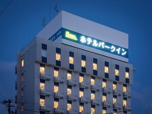 Un edificio de hotel con un letrero en japonés, varios balcones y un estilo arquitectónico moderno.