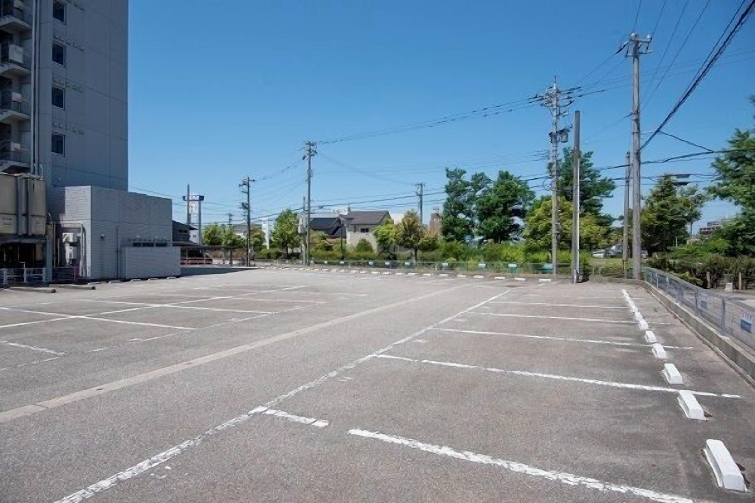 A parking lot with marked parking spaces and a building in the background.