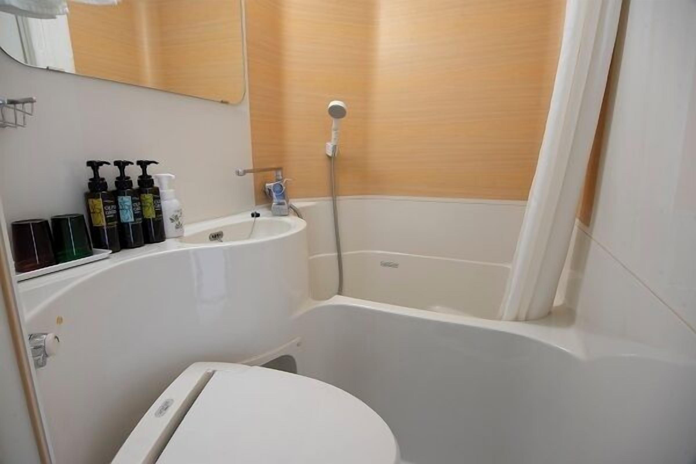 Een badkamer met een badkuip, een wastafel en toiletartikelen op het aanrecht.