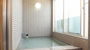 A small, enclosed hot tub area with tiled walls and floor, a window, and a light fixture. - Hotel Park Inn Takaoka (Takaoka)