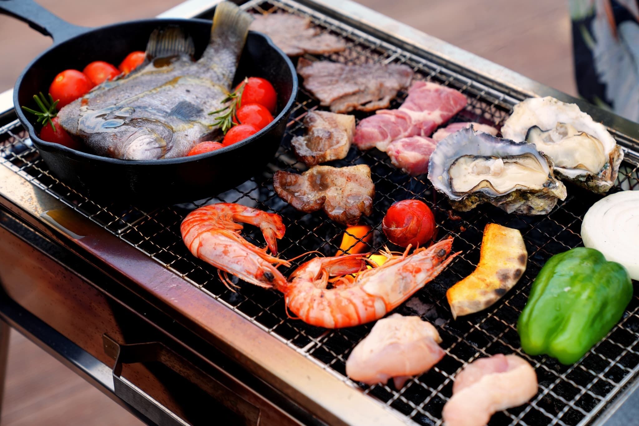 Diverse zeevruchten en vlees worden op een barbecue gegrild.