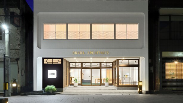 Un bâtiment moderne avec une enseigne indiquant « OKADA ARCHITECTS » et une autre indiquant « ROOM ».