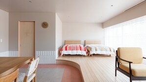 Une chambre moderne avec un plancher en bois, un banc incurvé, une table en bois, deux lits avec une literie à rayures et une grande fenêtre.
