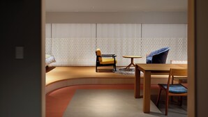 Un intérieur moderne avec un banc en bois aux lignes courbes, une table ronde et deux chaises.