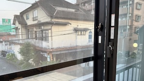 A view through a window with a house and a sign in the background. - Business Hotel Hinokiya (Hitoyoshi)