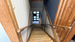 A wooden staircase with a metal handrail leading to a room with a large window. - Business Hotel Hinokiya (Hitoyoshi)